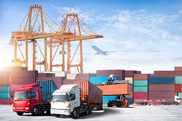 Image of a shipping yard with cranes, semi trucks, and shipping containers