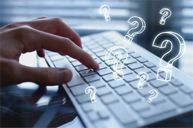 Photo of a hand typing on a keyboard flanked by white question marks